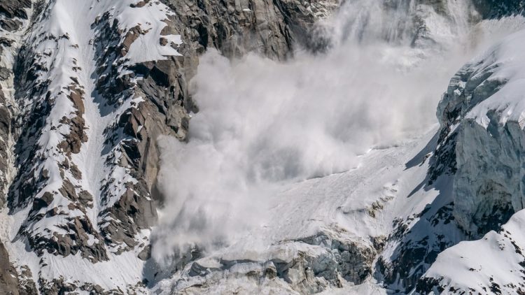 Avalanche rolling down a rocky mountain.